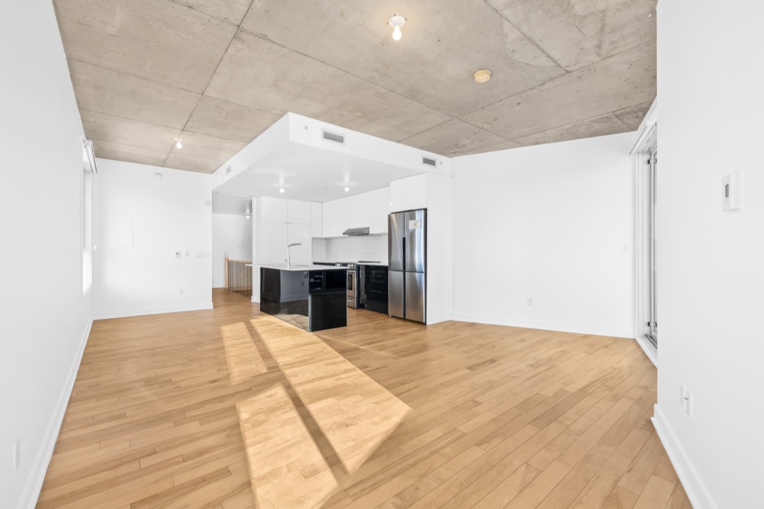 Grand séjour lumineux d'un condo à Rosemont, plafond de béton et planchers de bois franc